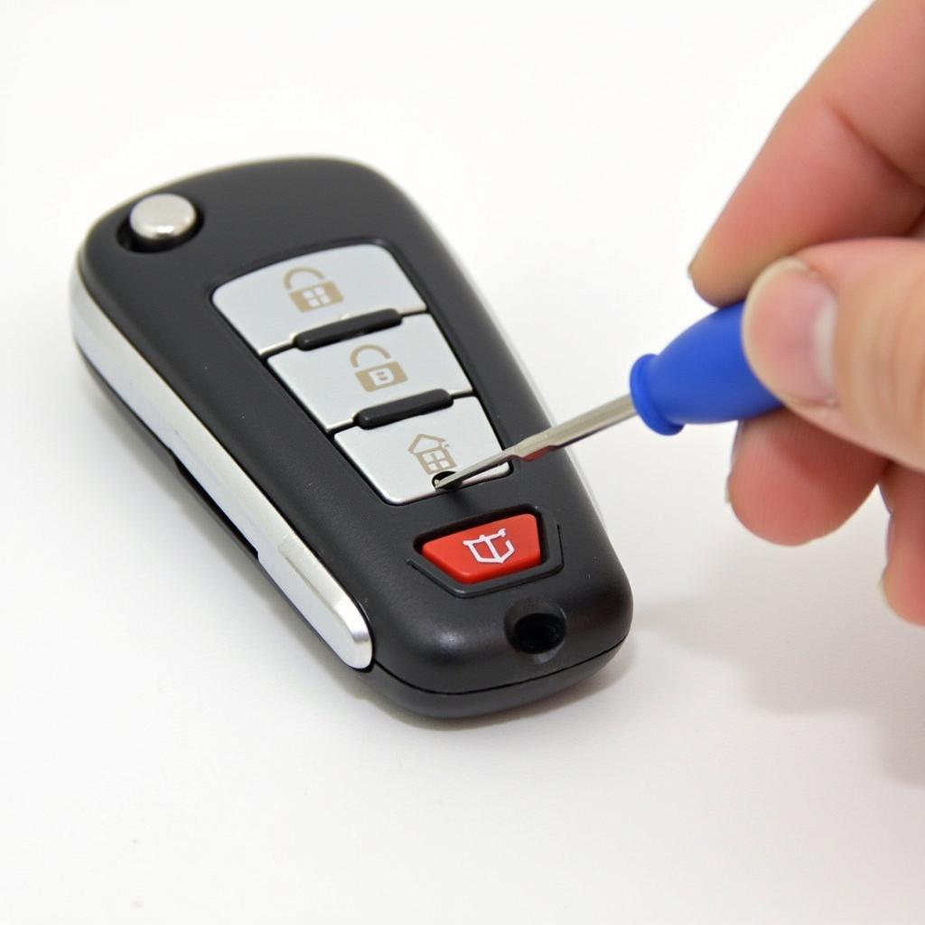 Removing the old battery from a 2017 Chrysler key fob: Detailed image showing the correct way to remove the old battery using a small flathead screwdriver.