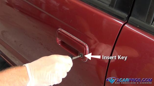 Inserting car key into door lock to manually lock the vehicle, a step in resetting the security system.