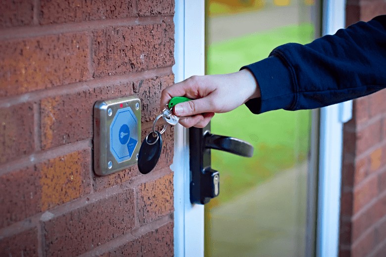 Close-up of a person tapping a key fob on a reader to enter an apartment building